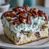 Butter Pecan Tres Leches Cake topped with creamy whipped cream and drizzled caramelized pecans.