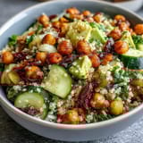 Vibrant grain bowl with roasted chickpeas, fresh vegetables, and zesty lemon vinaigrette drizzled on top.