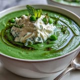 Creamy spring pea soup topped with airy whipped ricotta, ready to serve.