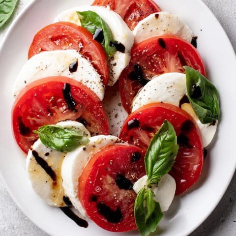 Plated Caprese Salad: colorful heirloom tomatoes layered with fresh basil and mozzarella.