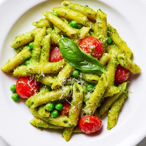 Green Pesto Pasta Salad served in a rustic dish, garnished with fresh basil leaves and a sprinkle of Parmesan, perfect for summer.