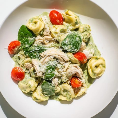Creamy Pesto Tortellini Skillet served in a rustic dish, garnished with fresh basil and halved cherry tomatoes for color.