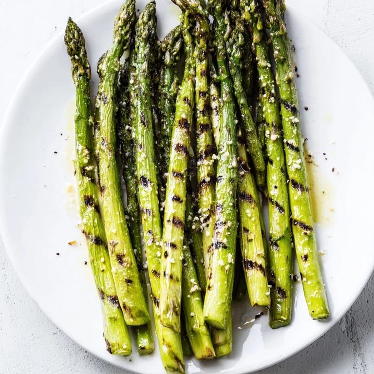 Vibrant green grilled asparagus glistening with olive oil beside lemon wedges, an easy, healthy side.