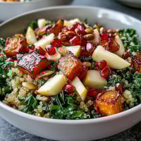 Roasted sweet potatoes and massaged kale in a vibrant Kale Harvest Grain Bowl with quinoa, apple, and pepitas.
