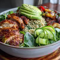 Golden pan-fried chicken slices rest atop a vibrant Paprika Roasted Vegetable Quinoa Bowl with creamy avocado.
